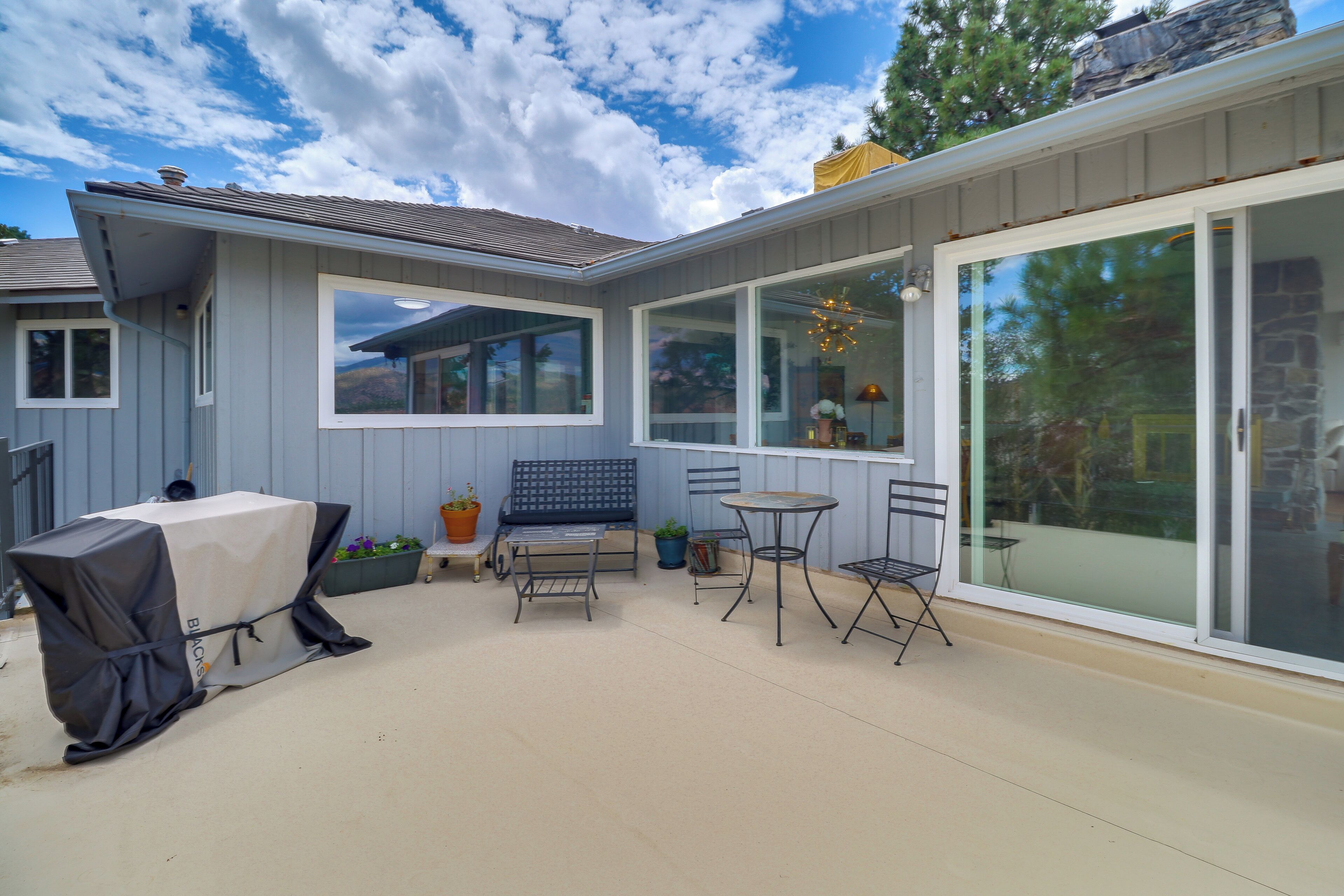 A patio with a covered grill, a bench, and two tables.