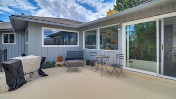 A patio with a covered grill, a bench, and two tables.
