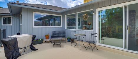 A patio with a covered grill, a bench, and two tables.