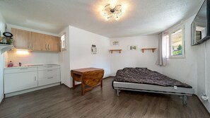 A compact room with a bed, a small wooden table, a kitchenette, and a ceiling light fixture. - Studio with views of the ski slopes and a mountain-themed area (Allos)