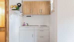 Una cucina compatta con mobili bianchi, un lavello e un piccolo piano di lavoro.