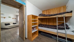 Una stanza piccola con un letto a castello, un'armadietto in legno e un divano.