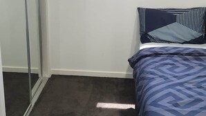 Quarto com cama, janela e porta deslizante.