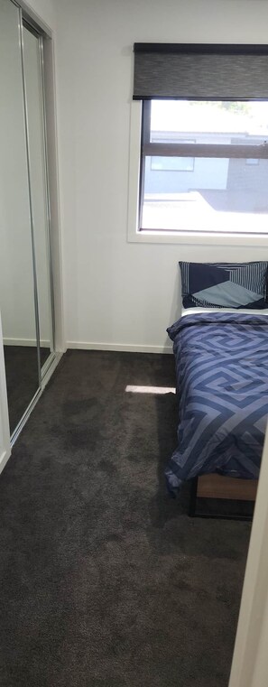 Ein Schlafzimmer mit einem Bett, einem Fenster und einer Schiebetür.
