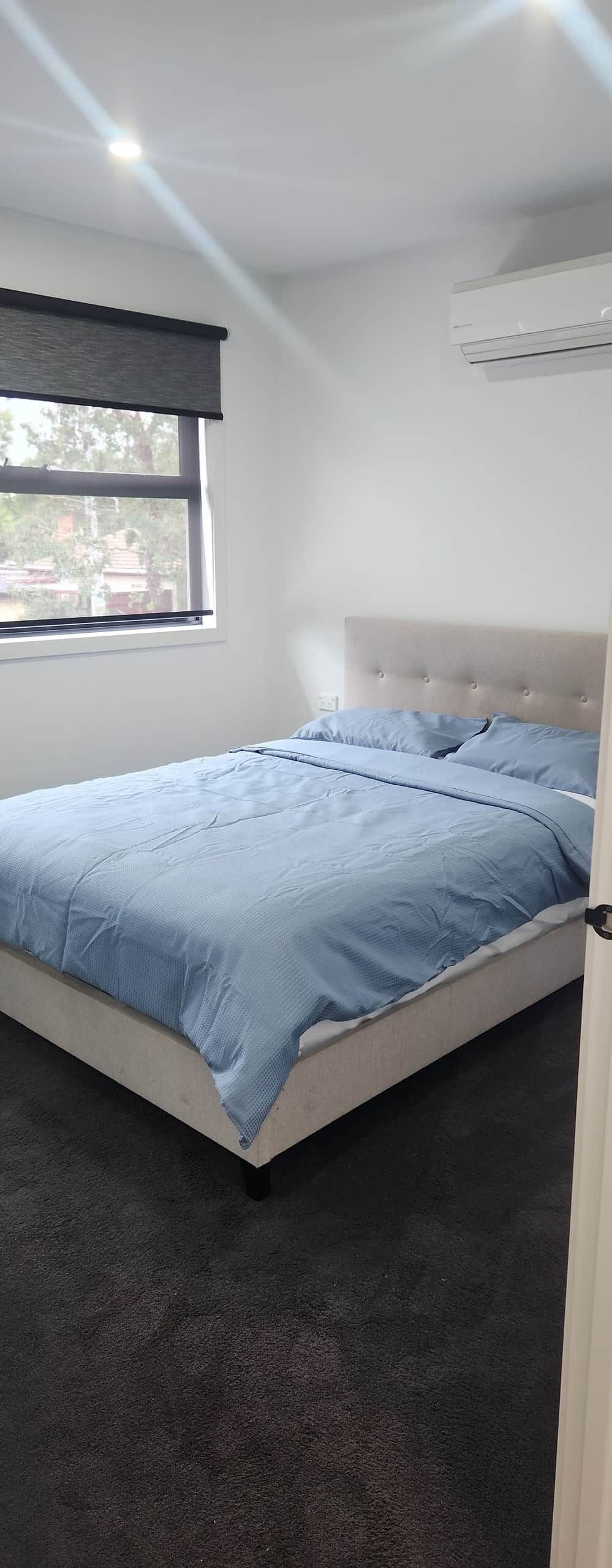 A bedroom with a bed, a window, and an air conditioning unit.