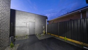 Um caminho de paralelepípedos leva a um edifício com fachada de tijolos e cerca de metal.