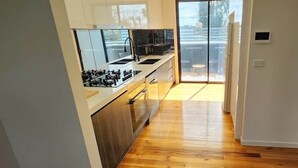 Eine moderne Küche mit Kochinsel, ein Essbereich mit Tisch und Stühlen sowie eine Glastür, die zu einem Außenbereich führt.