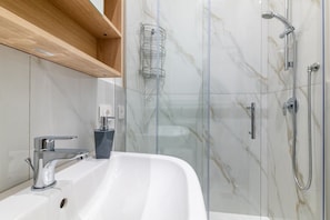 Un baño moderno con lavamanos blanco, grifo cromado y cabina de ducha con paredes de vidrio.