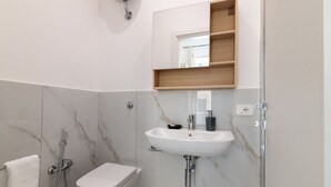 Casa de banho com sanita, lavatório e chuveiro.
