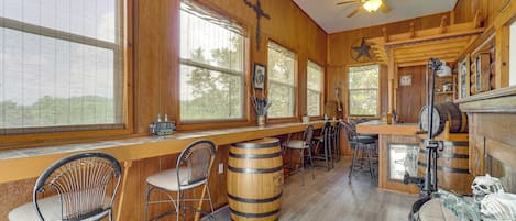 Un coin bar au style rustique, avec des murs en bois, de grandes fenêtres et un ventilateur de plafond.