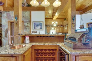 A kitchen with wooden cabinets, a granite countertop, a built-in wine rack, and a hanging light fixture. - 'Castlewoods' 8BR Estate Near Knoxville (Lenoir City)
