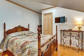 Ein Schlafzimmer mit einem hölzernen Himmelbett, einem an der Wand montierten Fernseher und einem Nachttisch mit Lampe.