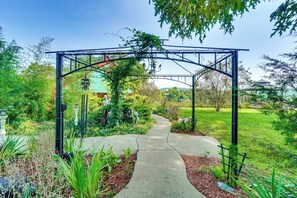 Ein Gartenweg führt zu einem Metallbogen mit einer Bank und einer Laterne.
