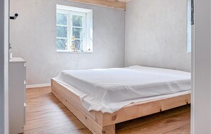 A bedroom with a wooden bed, a window with a view of trees, and a white wall. - Cozy home in Højer with WiFi (Højer)