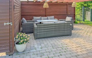 An outdoor seating area with wicker furniture, a table, and a potted plant. - Cozy home in Højer with WiFi (Højer)