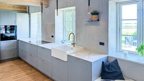 A modern kitchen with a built-in sink, stainless steel appliances, and a window overlooking a garden. - Cozy home in Højer with WiFi (Højer)
