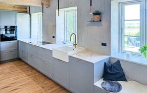 A modern kitchen with a built-in sink, stainless steel appliances, and a window overlooking a garden. - Cozy home in Højer with WiFi (Højer)