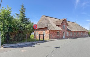 A traditional brick building with a thatched roof, a red circular sign with a crest, and a clear sky. - Cozy home in Højer with WiFi (Højer)