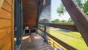 A wooden deck with a view of a grassy field and a fence.