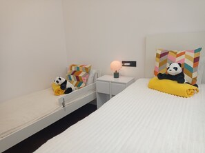 Ein Hotelzimmer mit einem Bett, einem Nachttisch mit Lampe und einem Sessel mit farbenfrohem Kissen.