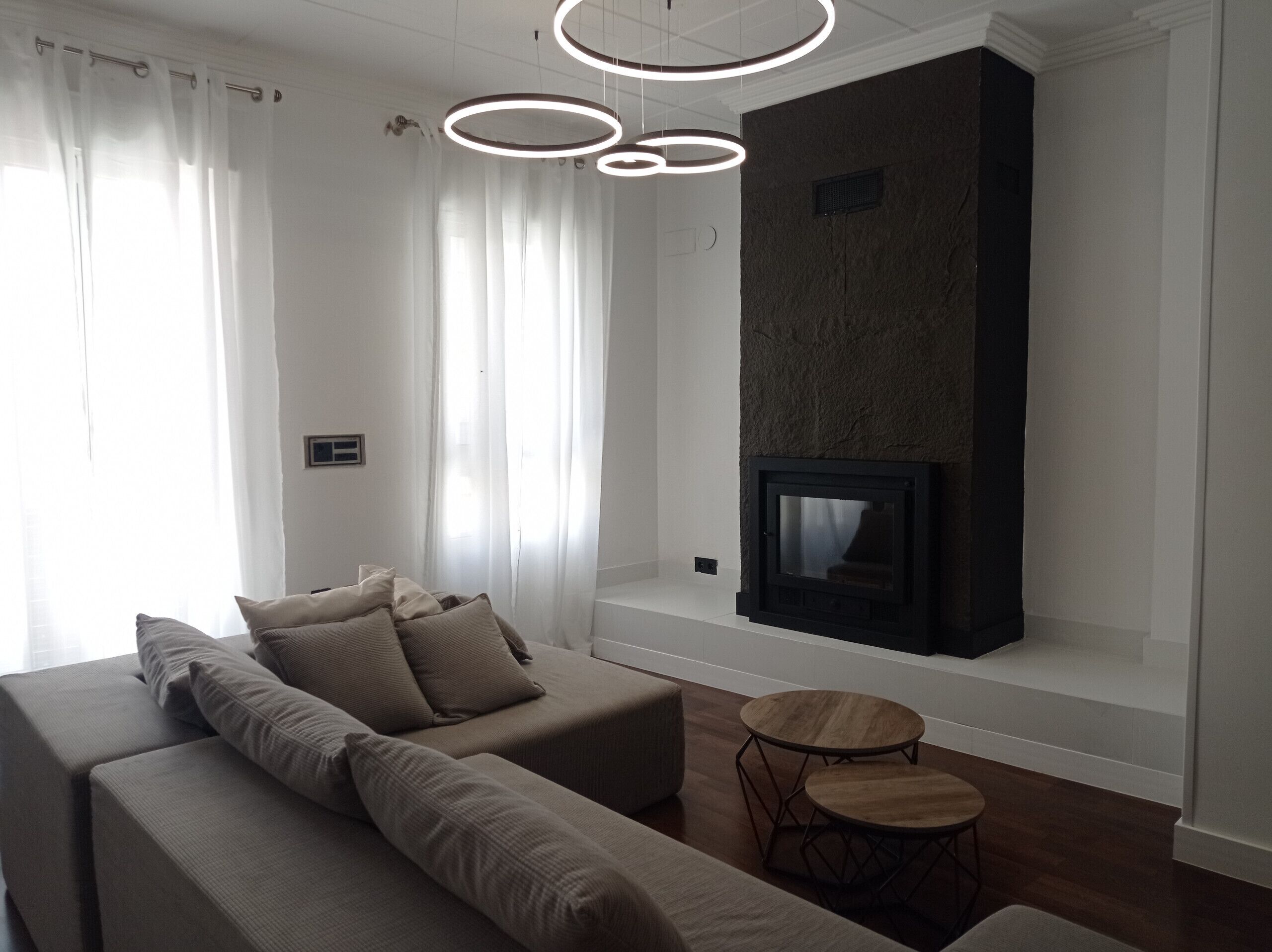 A modern living room with a sofa, a fireplace, and a round wooden table.