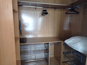 Ein begehbarer Kleiderschrank mit Bett, Metalltrocknergestellen und einem Holzschrank.