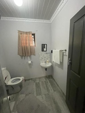 A bathroom with a toilet, sink, and towel rack. - OlimG Stays (KuGompo City)