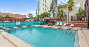 A swimming pool with lounge chairs and a covered seating area. - PCB Beach Home with Gulf Access, Pool, and more (Panama City Beach)
