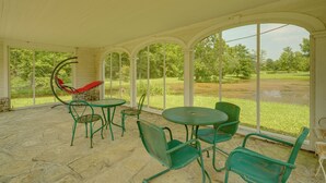 A covered patio with a hammock, green metal chairs, and a table. - Ride, Swim & Hike! Koalin Farms Cottage (Belleview)