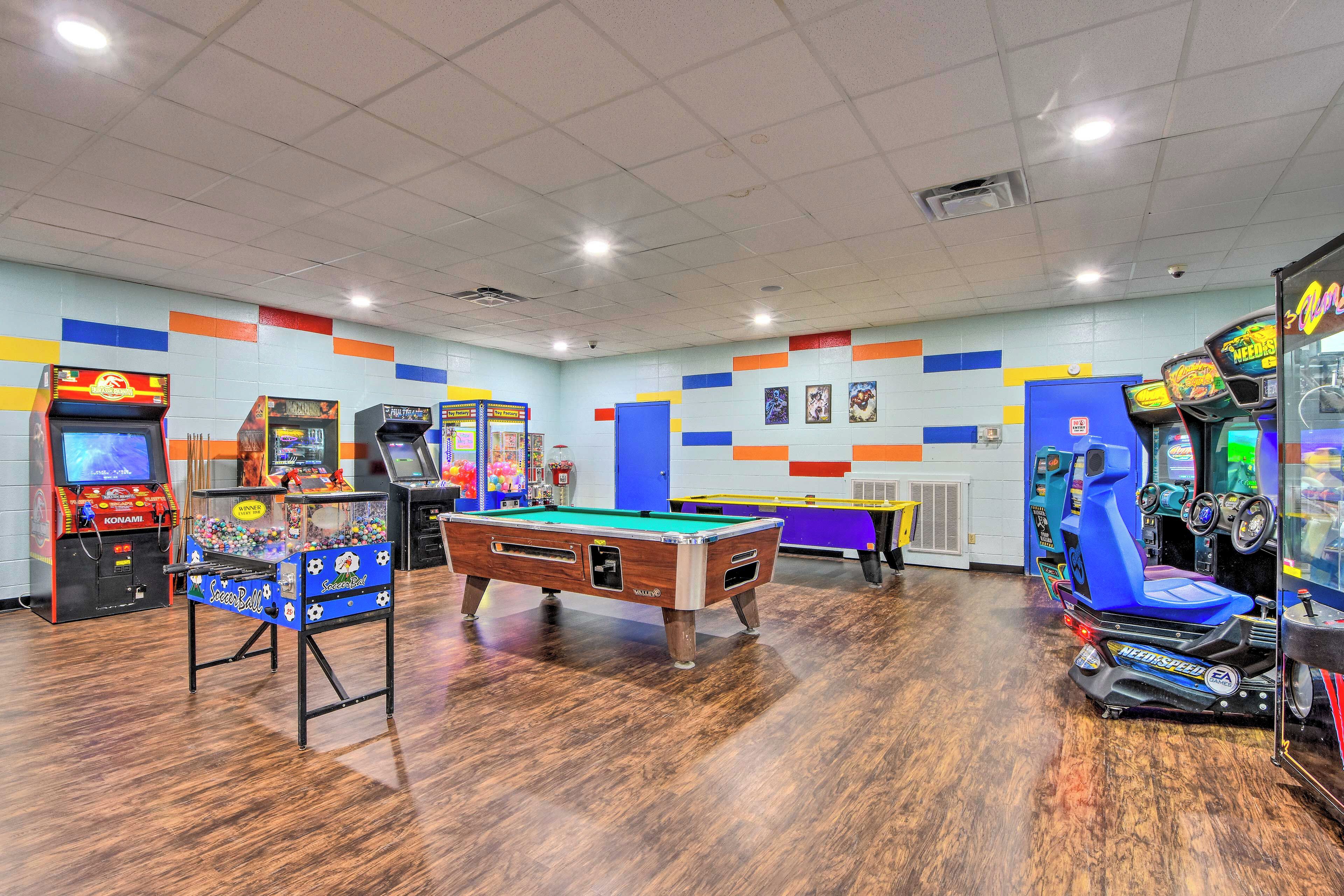 A recreational room with a pool table, arcade games, and a blue racing game machine.