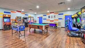 A recreational room with a pool table, arcade games, and a blue racing game machine.