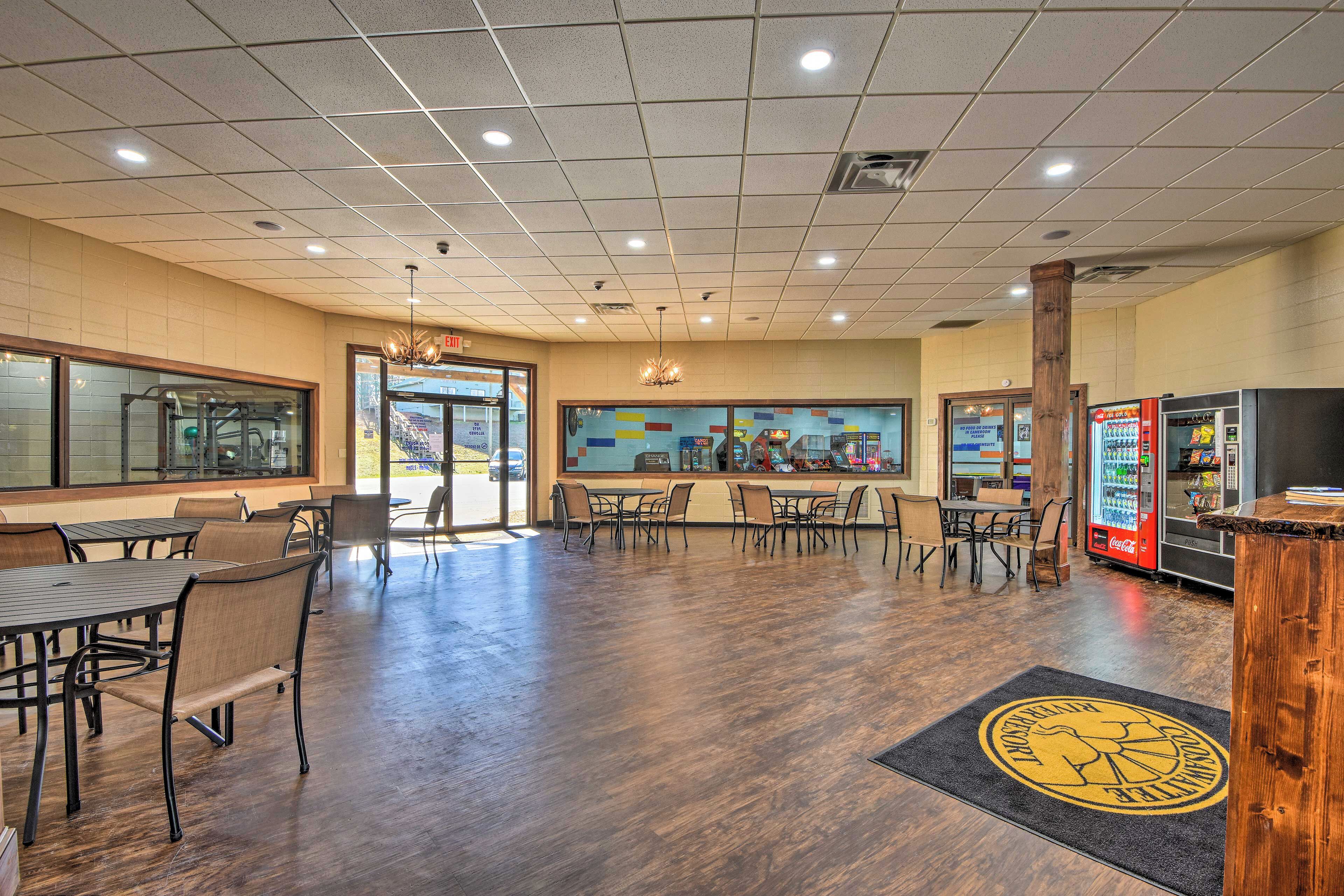 A spacious indoor area with multiple tables and chairs, a vending machine, and a large window.