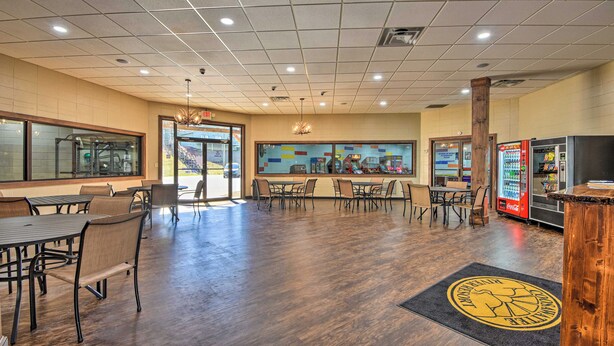 A spacious indoor area with multiple tables and chairs, a vending machine, and a large window.