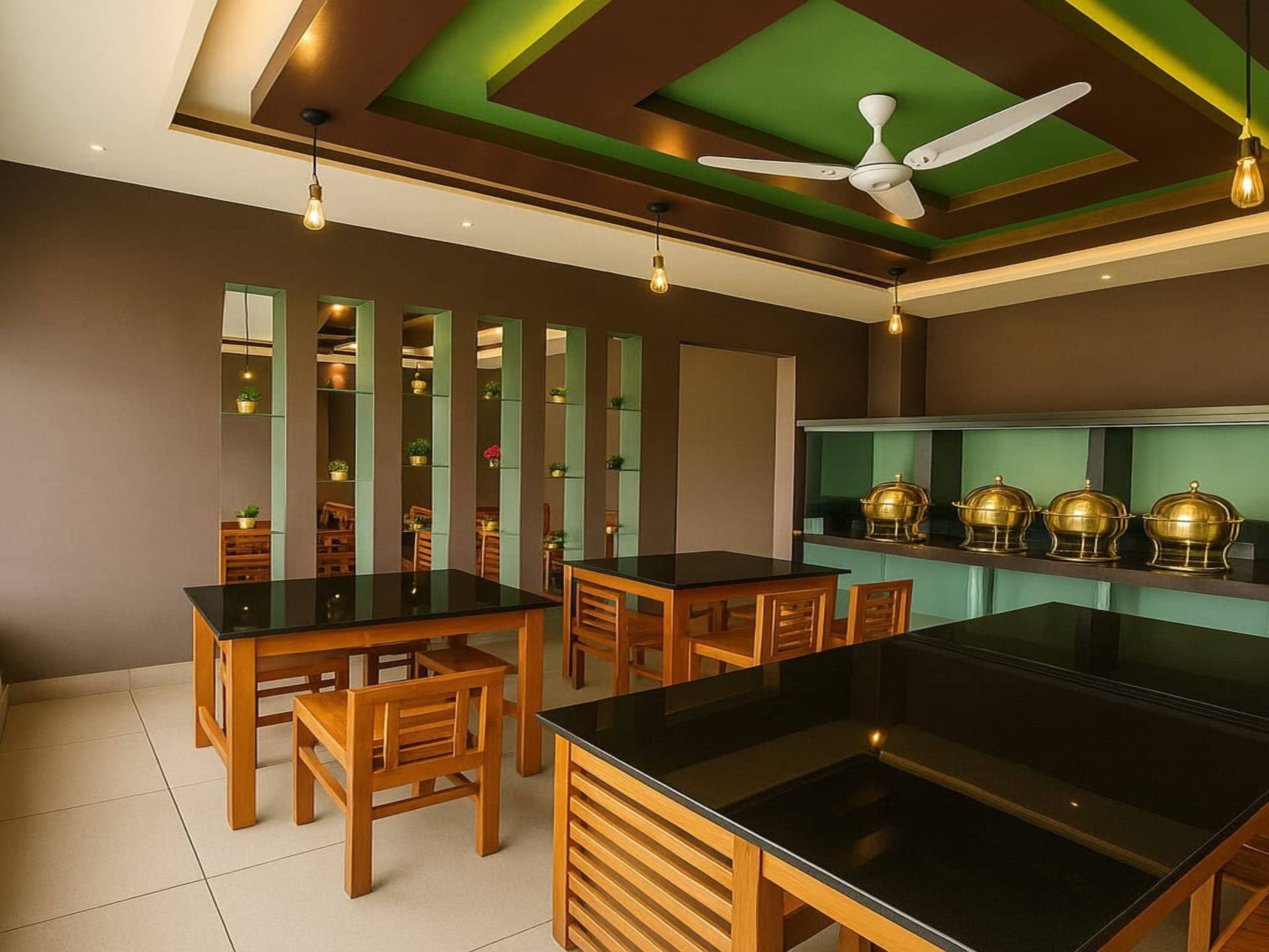 A modern kitchen with black countertops, wooden chairs, and a ceiling fan.