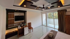 A modern hotel room with a large bed, a desk, a chair, a television, and a balcony with a view. - Tripple F Inn - A Luxury Stay in Munnar (Munnar)