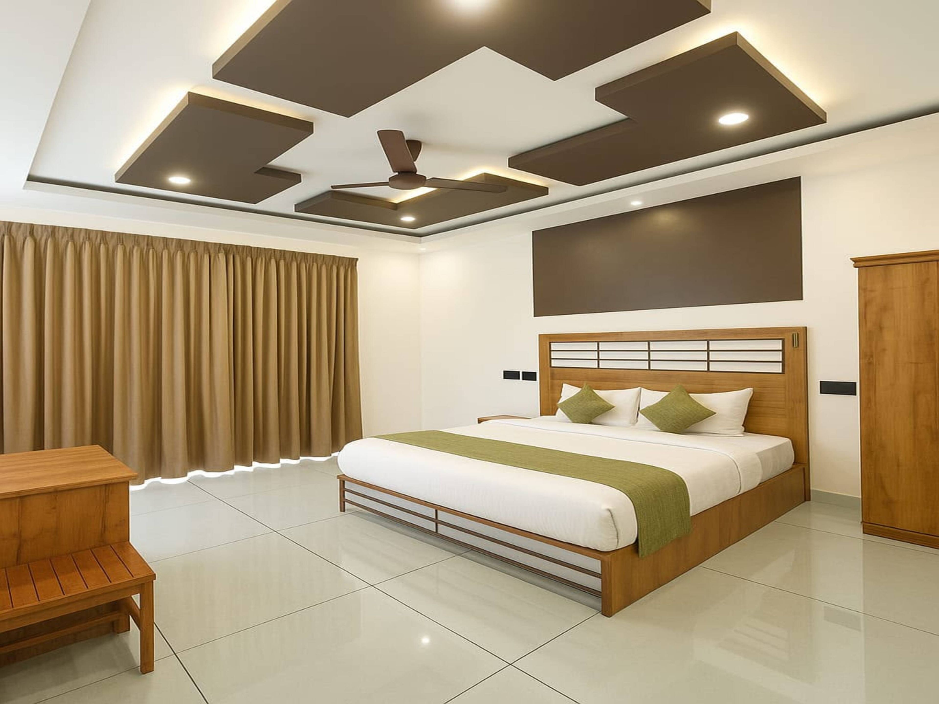 A modern bedroom with a bed, a desk, and a ceiling fan.