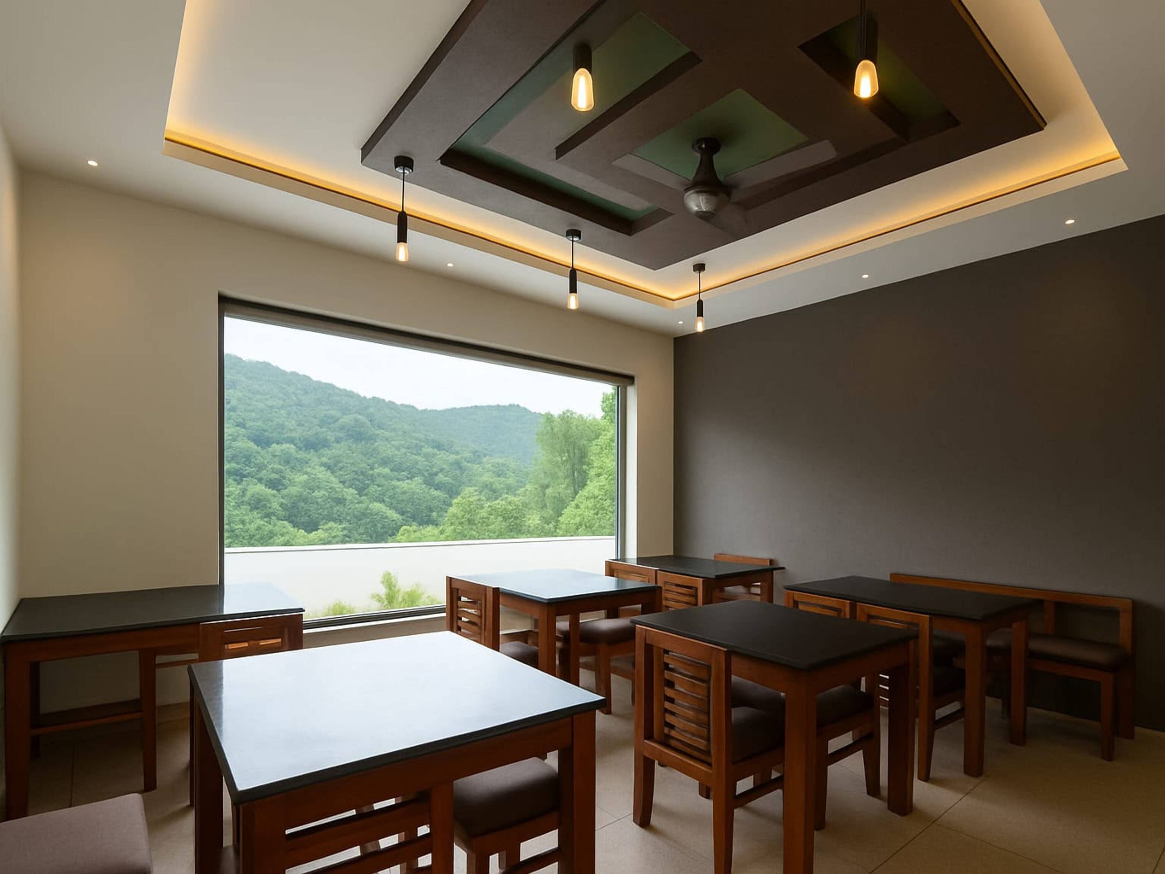 Un comedor con varias mesas y sillas, un ventanal que ofrece vistas a un paisaje boscoso y un diseño de techo moderno con iluminación empotrada.