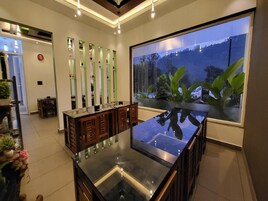 Interior moderno com mesa de vidro central, armários de madeira e uma janela ampla com vista para uma paisagem montanhosa.