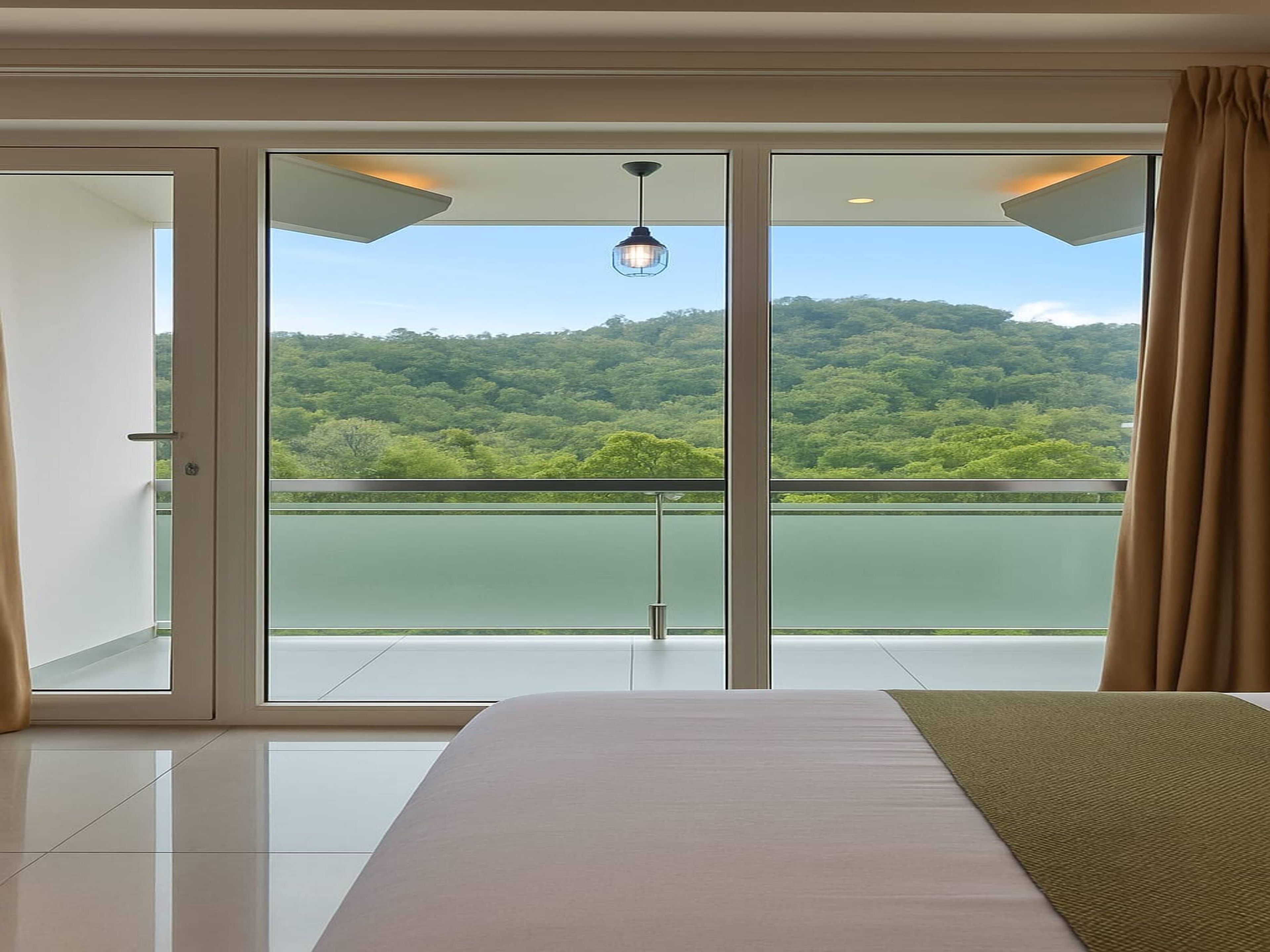 A bedroom with a large bed, a view of a lake, and a balcony with a glass door.