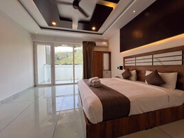 Quarto de hotel moderno com uma cama grande, um ventilador de teto e vista para um corpo d'água através da porta de correr de vidro.