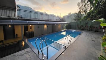 A rectangular swimming pool with a metal ladder, surrounded by a concrete deck.