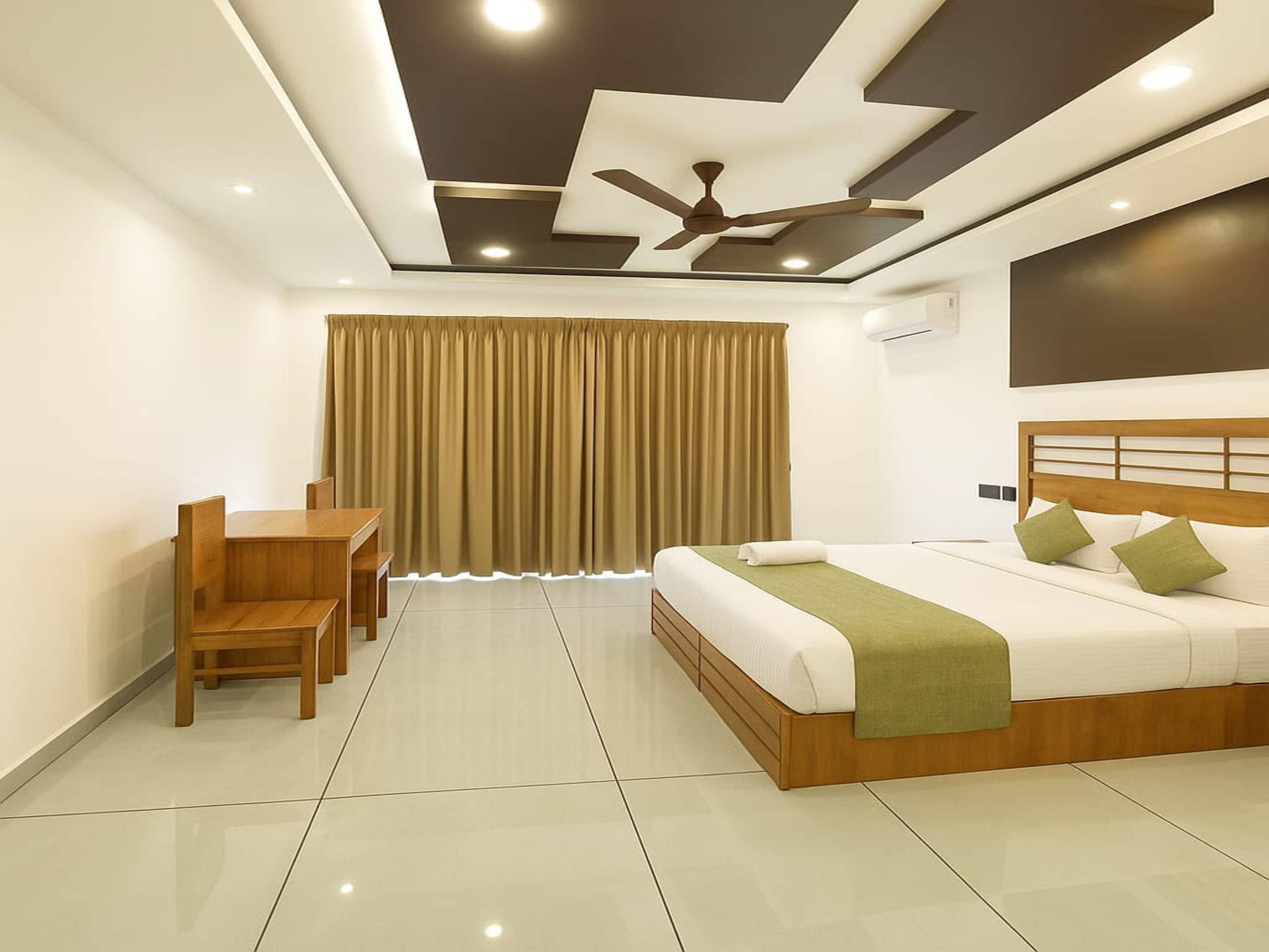 A modern hotel room with a bed, a desk, and a chair.