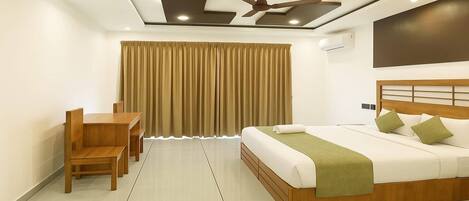 A modern hotel room with a bed, a desk, and a chair.