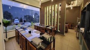 A modern interior with a dining area featuring wooden furniture and a large window overlooking a parking area. - Tripple F Inn - A Luxury Stay in Munnar (Munnar)