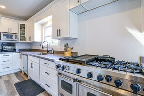 Een moderne keuken met witte kasten, een inbouwoven, een gasfornuis en een magnetron.