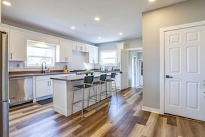 A modern kitchen with white cabinets, a central island with bar stools, and a stainless steel Viking range. - Bay Views + Stargazing! Spacious Mount Vernon Home (Mount Vernon)