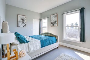 Een slaapkamer met een bed, een raam en kunstwerken aan de wanden.