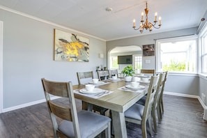 A dining area with a wooden table and chairs, a chandelier, and a painting on the wall. - Bay Views + Stargazing! Spacious Mount Vernon Home (Mount Vernon)