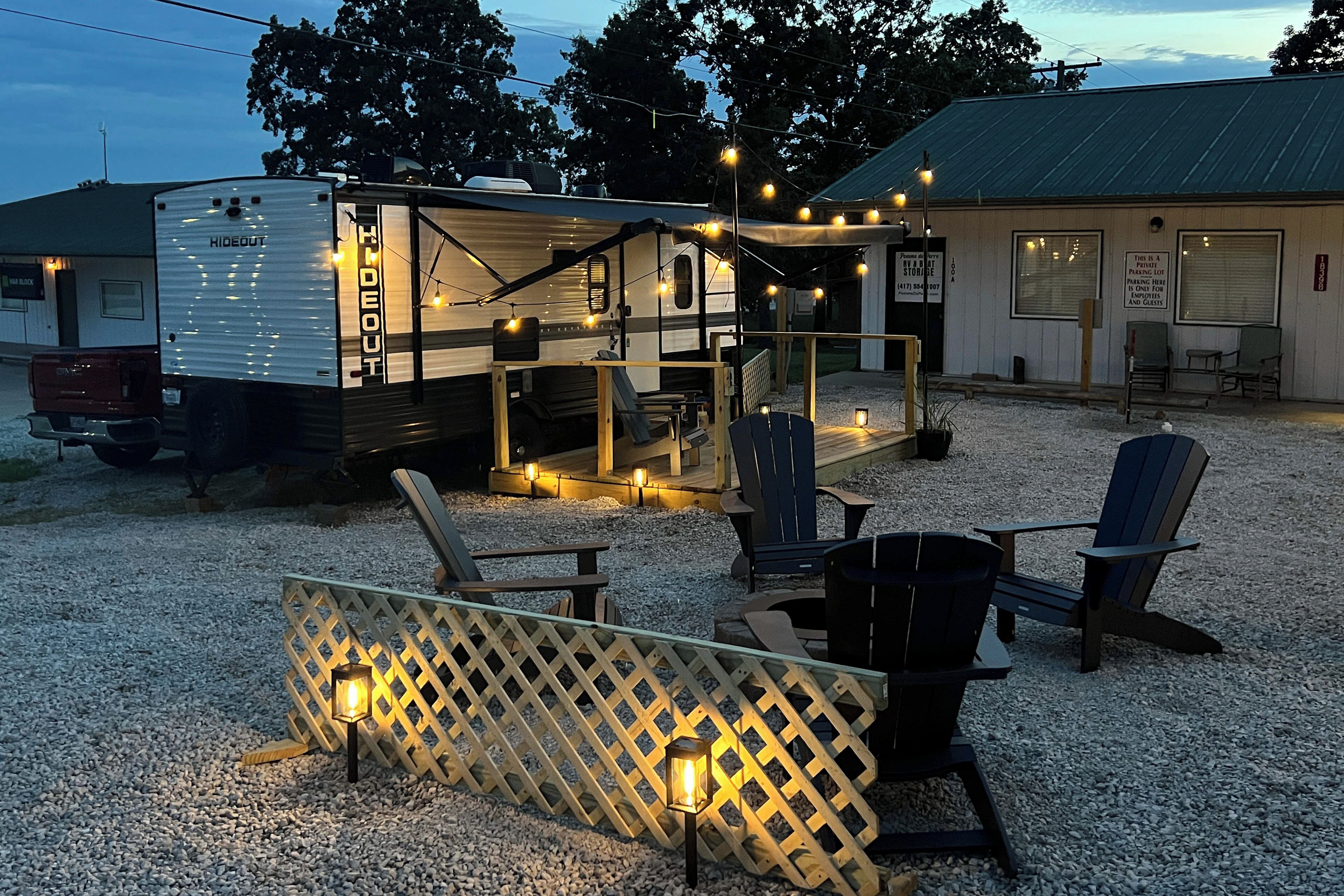 A campsite with RVs, outdoor seating, and a building with a sign.