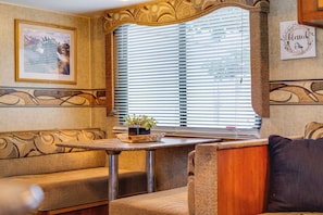 Ein gemütliches Interieur mit einer Couch, einem kleinen Tisch mit Pflanze und einem Fenster mit Jalousien.